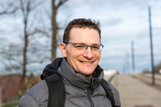 Attractive forty year old man with glasses and a winter jacket, posing in a natural environment
