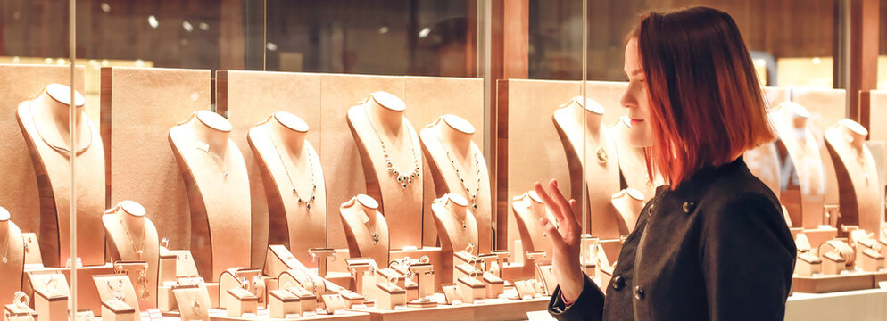 Pretty Woman Looking At Jewelry In Store Window. Customer Near Jewellery. Dreamy Red Hair Girl Chooses Silver, Gold, Diamonds, Precious Stones. Banner