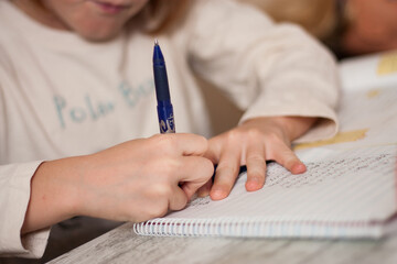 manos de chico escribiendo en su cuaderno deberes en una mesa