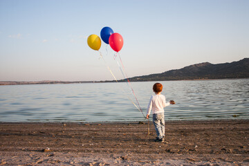 niño con globos en un lago