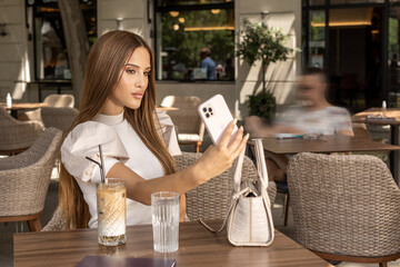 Beautiful young woman taking selfie in a cafe bar