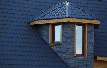 The roof is made of blue metal tiles. Covering the roof of a garden house with metal roof tiles. Built-in windows in the wall of the building. Double-glazed windows installed in the cottage. © EVGENY
