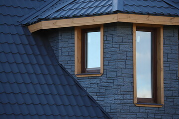 The roof is made of blue metal tiles. Covering the roof of a garden house with metal roof tiles. Built-in windows in the wall of the building. Double-glazed windows installed in the cottage.