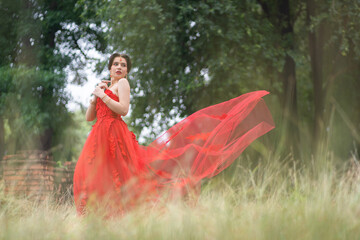 Beautiful portrait pretty woman red dressed as an Indian sexy girl with red lips. Young Hindu Pakistani Bride and glamour makeup in a fashion jewelry set.