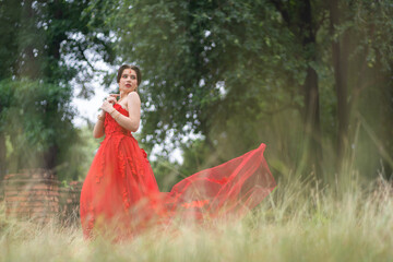 Fototapeta premium Beautiful portrait pretty woman red dressed as an Indian sexy girl with red lips. Young Hindu Pakistani Bride and glamour makeup in a fashion jewelry set.