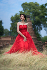 Fototapeta premium Beautiful portrait pretty woman red dressed as an Indian sexy girl with red lips. Young Hindu Pakistani Bride and glamour makeup in a fashion jewelry set.