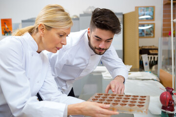 young chocolatier observing chocolates in the mold