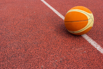 Orange ball for basketball lying on the sport court.Sport red court outdoor .Copy space.Top view