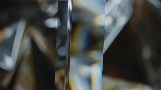 Selective focus close up shot of glass prism hanging and dispersing light on metallic background