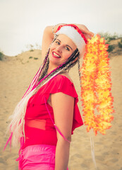 Happy middle aged attractive brunette woman in red swimsuit and Santa hat having fun on the coast. Christmas holiday vacation and travel concept.