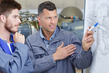 engineer and his apprentice looking at detailed drawings