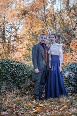 Vampire man wearing victorian suit with vampire woman in the autumn forest. Vintage medieval concept style.