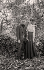Vampire man wearing victorian suit with vampire woman in the autumn forest. Vintage medieval concept style.
