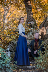 Vampire man wearing victorian suit with vampire woman in the autumn forest. Vintage medieval concept style.