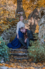 Vampire man wearing victorian suit with vampire woman in the autumn forest. Vintage medieval concept style.