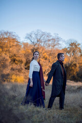 Vampire man wearing victorian suit with vampire woman in the autumn forest. Vintage medieval concept style.