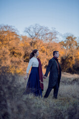 Vampire man wearing victorian suit with vampire woman in the autumn forest. Vintage medieval concept style.