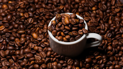 Espresso cup filled with coffee beans surrounded by a large number of coffee beans on a dark background close-up.