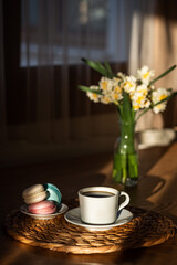 Cozy breakfast with cup of coffee, macaroons , flowers and open notebook on rustic wooden table. 