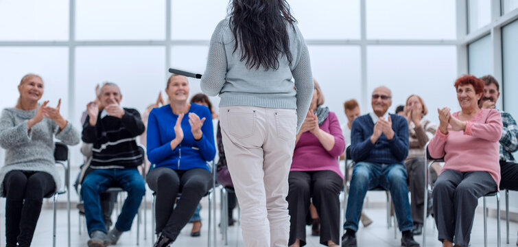 teacher with a folder in his hand teaches elderly people busines