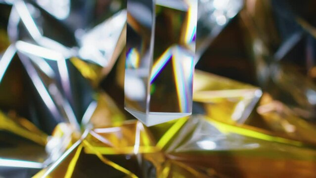 Abstract background with glass prism turning around and refracting light on blurry golden background