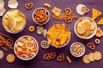 Salty snacks. Party food mix. Potato and tortilla chips, crackers and other appetizers in bowls,...