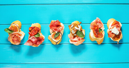 Appetizers board with traditional spanish tapas set. Italian antipasti bruschetta with prosciutto, cream cheese and fig