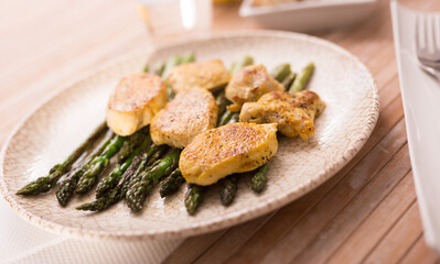fried chicken breast pieces with asparagus on white plate