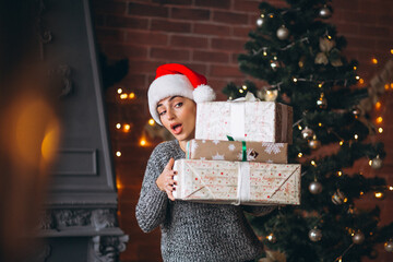 Woman with presents standing in front of christmas tree