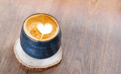 Cup of Latte art coffee with heart shape on old wooden background