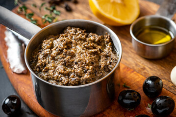 Tapenade in a bowl close-up and ingredients for making tapenade. French cuisine. Tapenade is made from olives, capers, anchovies and herbs.