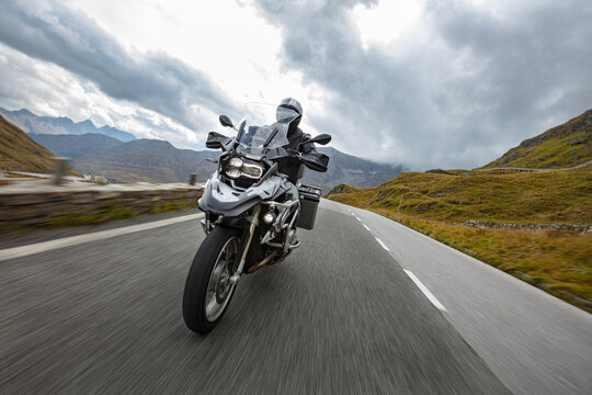 Motorbiker riding in Austrian Alps, dramatic sky. Travel and freedom, outdoor activities © Lukas Gojda