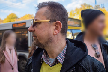 Man with beard in dark jacket and sunglasses walking in old town