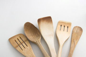 Cinq pelles et spatules de cuisine en bois naturel sur fond blanc