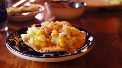 local mexican food, corn tostada with cucumber, in handmade ceramic plate with spicy powder