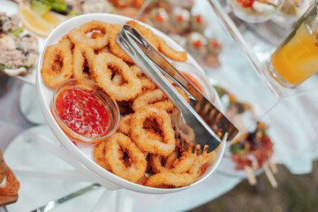 Calamari rings in batter with sauce on a white dish