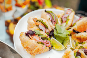 Croissant with meat and vegetables and greens on a white dish