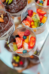 Fruit salad with berries in a glass bowl with a spoon