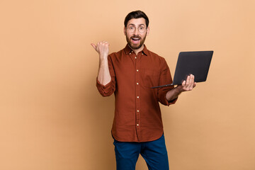 Portrait of excited positive person direct thumb finger empty space isolated on beige color background