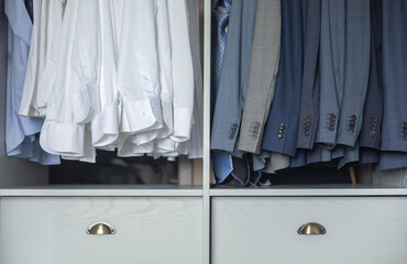 Business male wardrobe hanging white shirts blazer coat clothing on hangers dresser drawer closeup