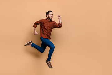 Fototapeta na wymiar Full body profile portrait of sporty energetic person jump running empty space isolated on beige color background