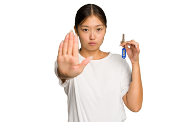 Young asian woman holding home keys isolated on green chroma background standing with outstretched hand showing stop sign, preventing you.