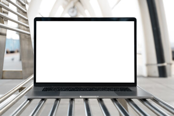 Laptop with white screen in railway station. Empty copy space, blank screen mockup. Soft focus laptop in railway station background. Travel, study and work outside office concept