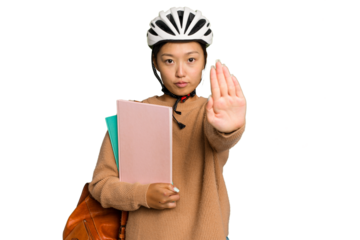 Young student asian woman wearing a bike helmet isolated on green chroma background standing with outstretched hand showing stop sign, preventing you.
