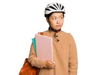 Young student asian woman wearing a bike helmet isolated on green chroma background confused, feels doubtful and unsure.
