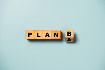 Flipping of wooden cube block from plan A to B on blue background for backup plan selection of business planing concept.