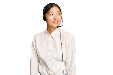 Telemarketer asian woman working with a headset isolated on green chroma background looks aside...