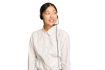 Telemarketer asian woman working with a headset isolated on green chroma background looks aside smiling, cheerful and pleasant.