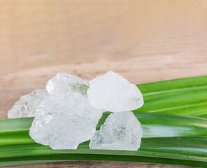 Crystal clear alum cubes or Potassium alum on green leaf. Chemical compound substance. Concept for beauty, spa and underarm treatment industrial.                                                      