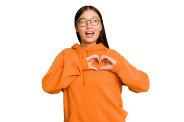 Young Asian woman isolated on green chroma background smiling and showing a heart shape with hands.